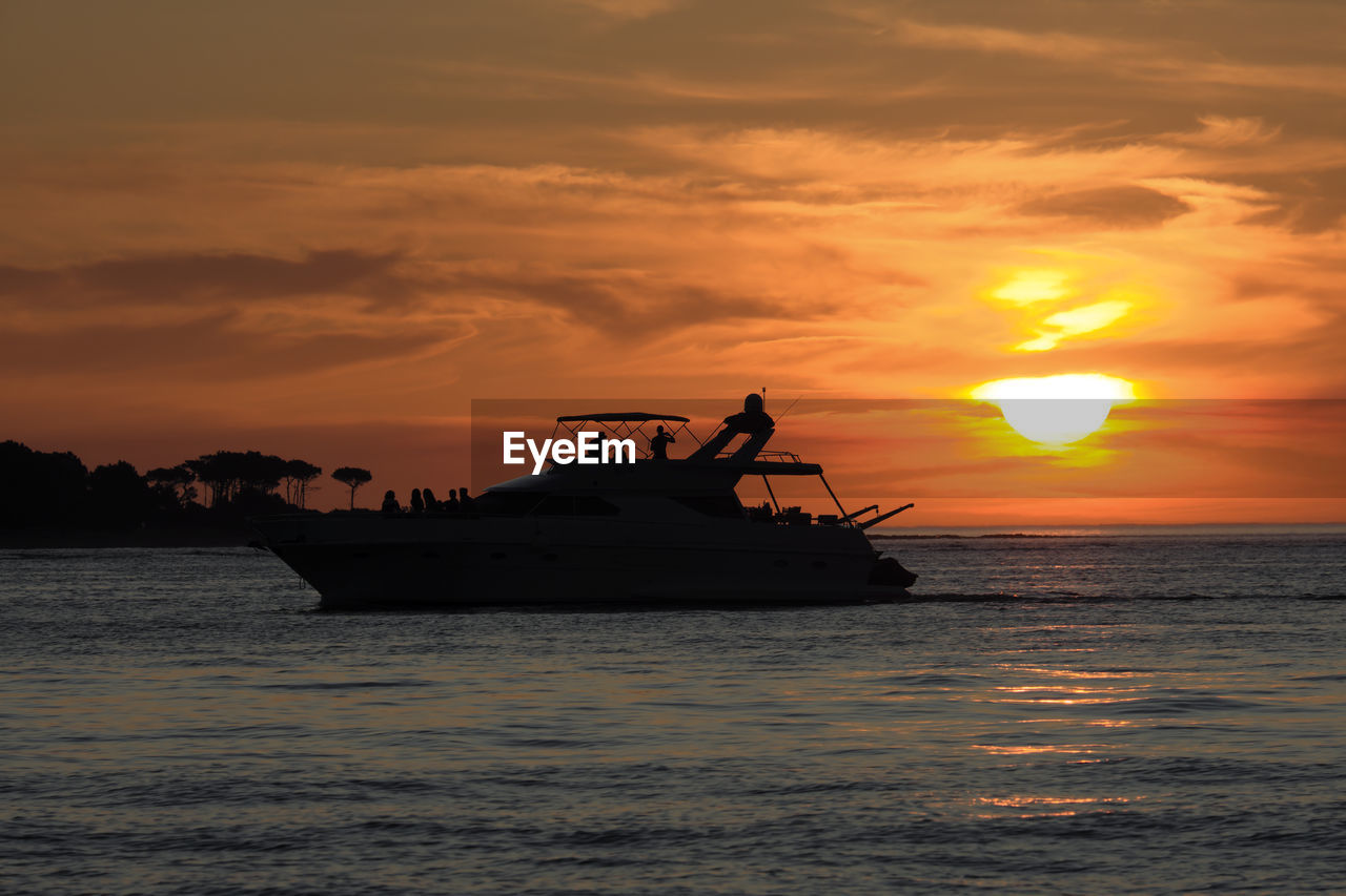 SILHOUETTE PEOPLE ON BOAT IN SEA AGAINST ORANGE SKY