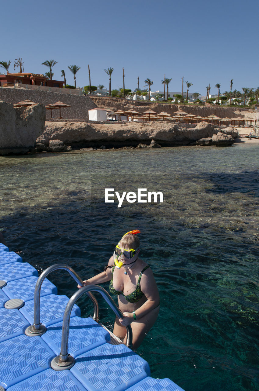 Plump girl in a green swimsuit and a swimming mask, dives and swims in the sea