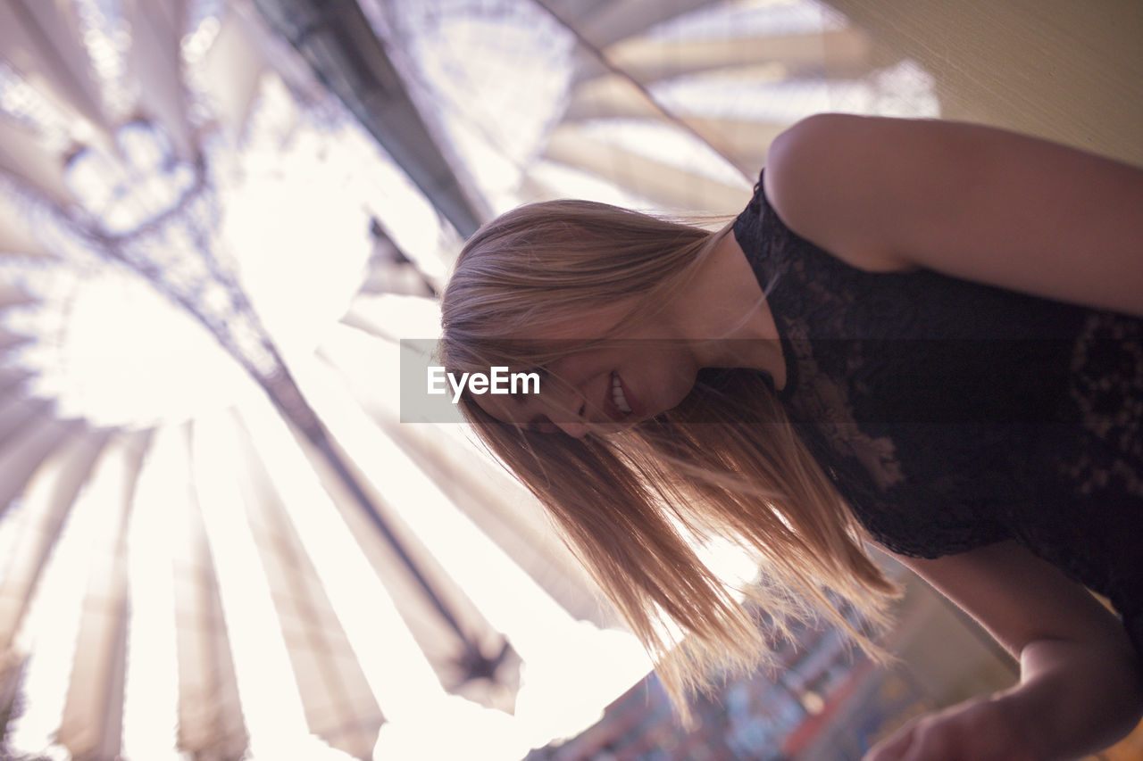 Low angle view of woman against illuminated chandelier