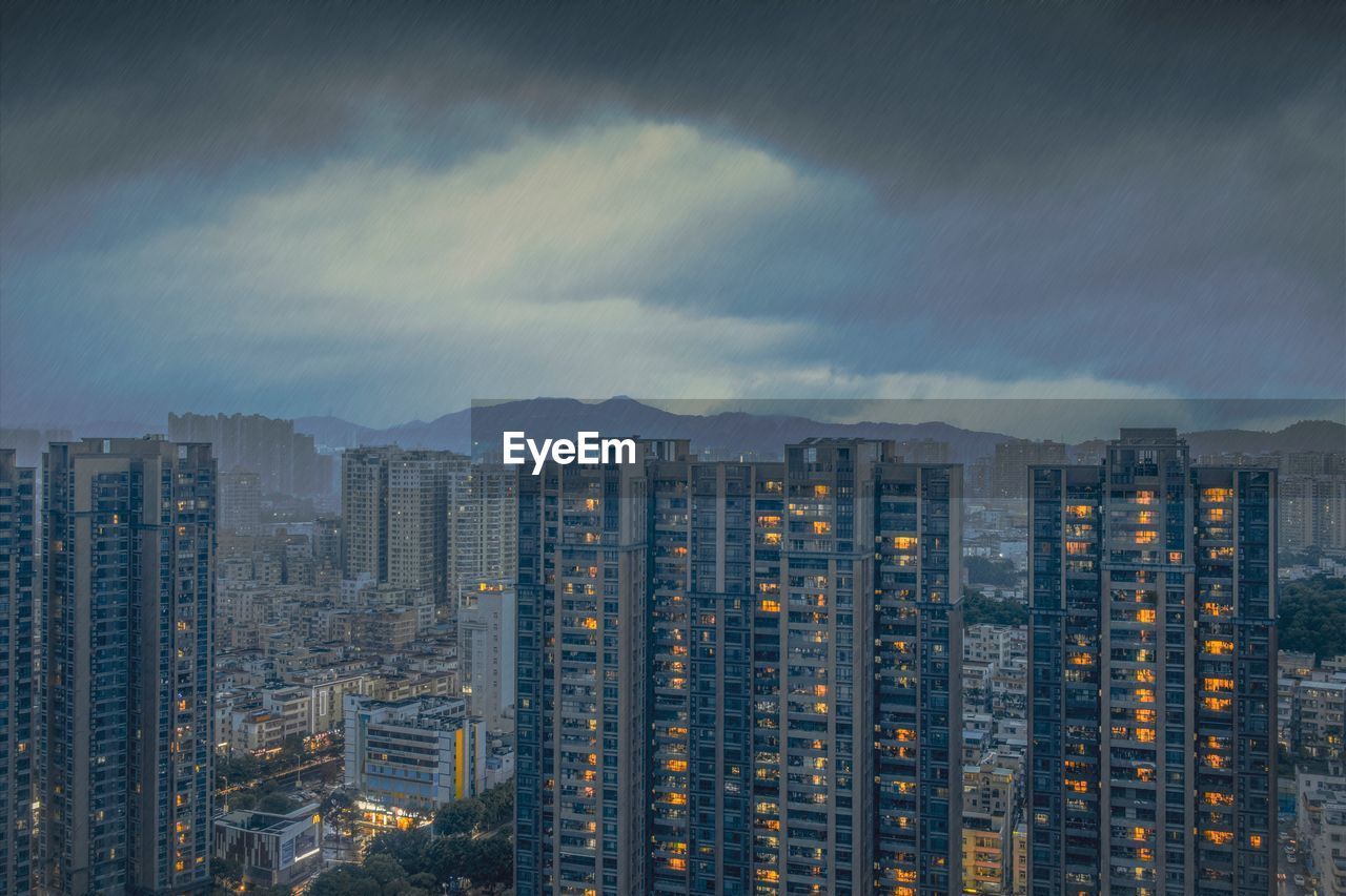 Modern buildings in city against sky at dusk