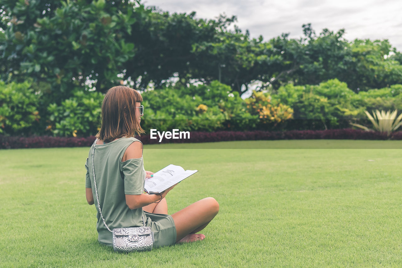 Girl on the lawn in the park reads a book