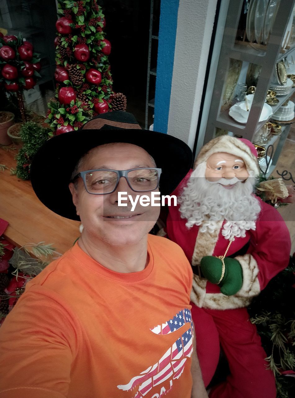 High angle portrait of man standing against santa claus statue