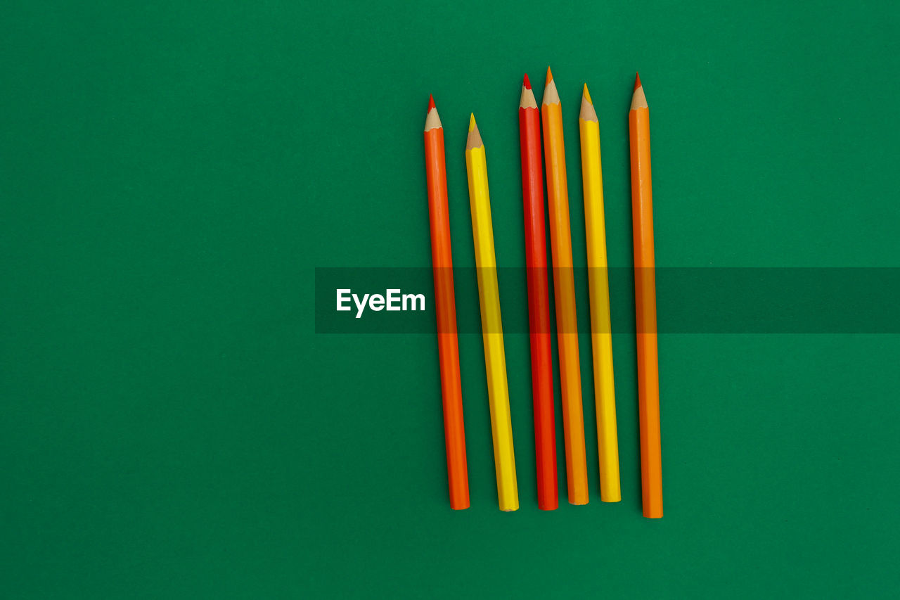 Close-up of multi colored pencils over green background