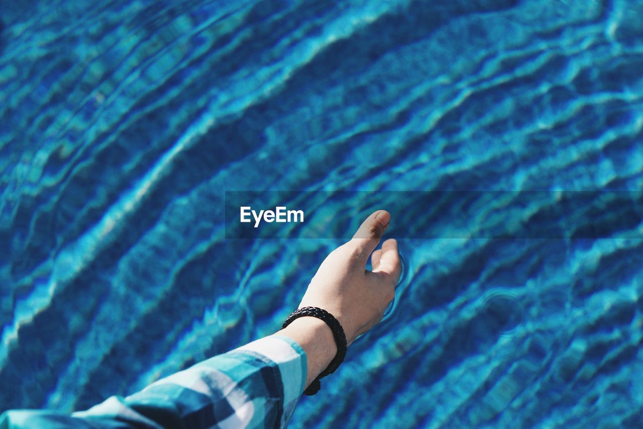 Cropped hand of man by swimming pool