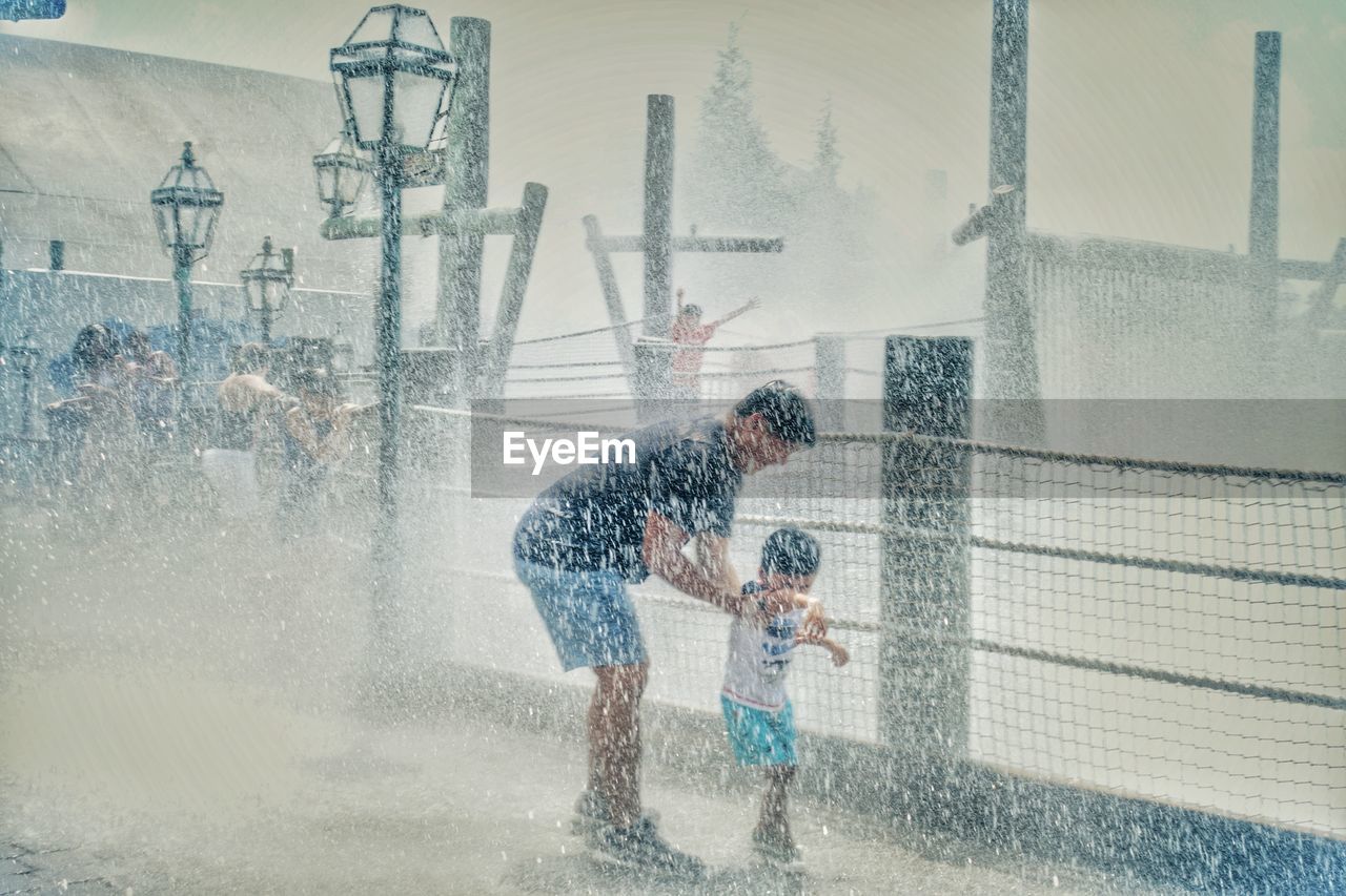 MEN PLAYING WITH UMBRELLA AT WATER