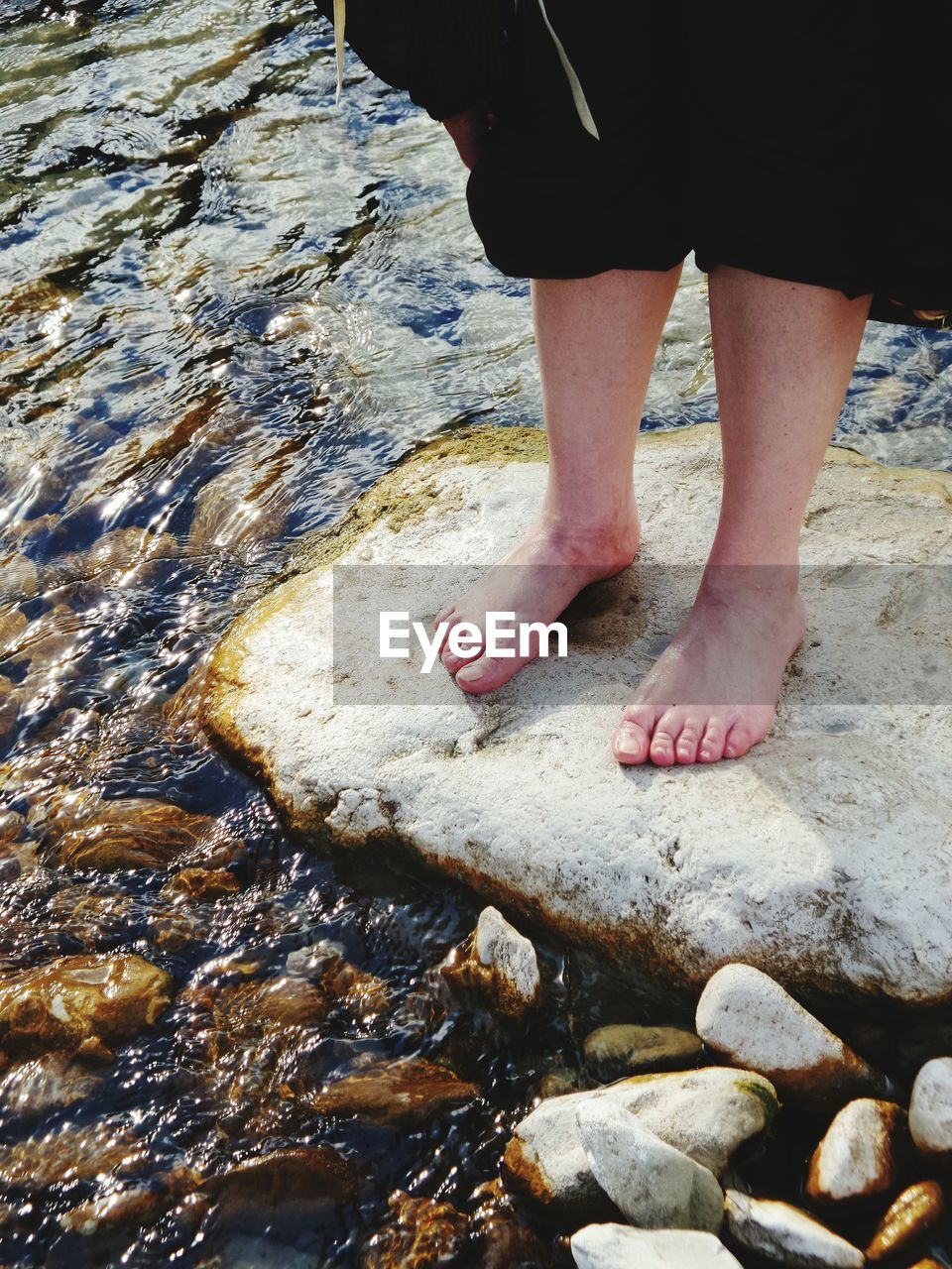 LOW SECTION OF WOMAN STANDING ON WATER