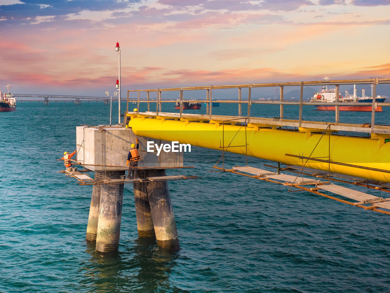 Workers are repairing and painting bollard for mooring on sea at industrial port