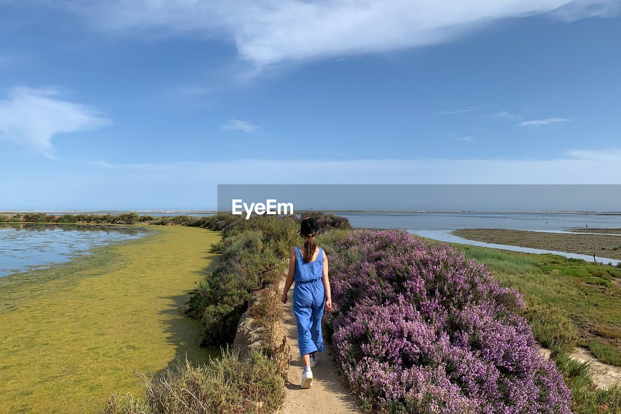 Rear view of woman walking on land against sky