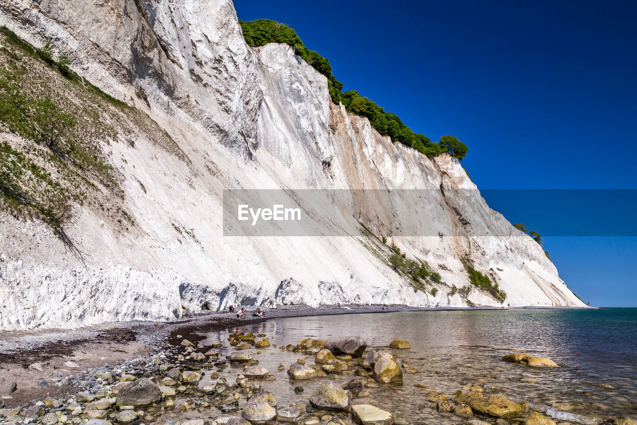 SCENIC VIEW OF SEA BY MOUNTAIN AGAINST CLEAR SKY