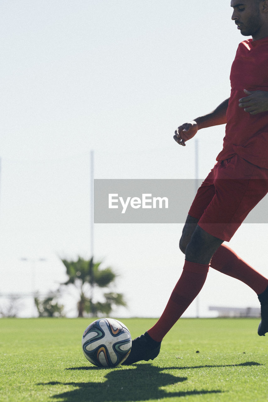 African american male soccer player practicing on grass pitch