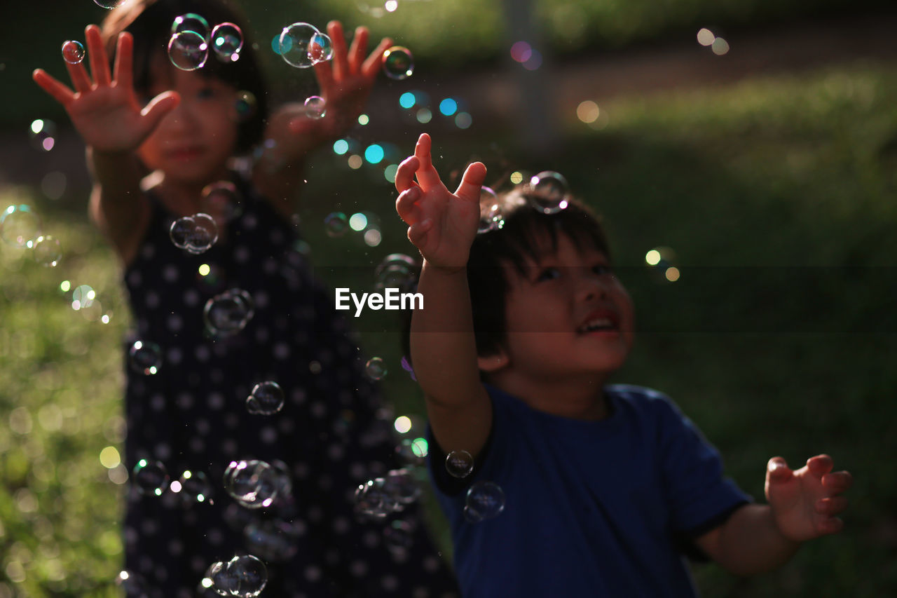 High angle view of siblings playing with bubbles at park