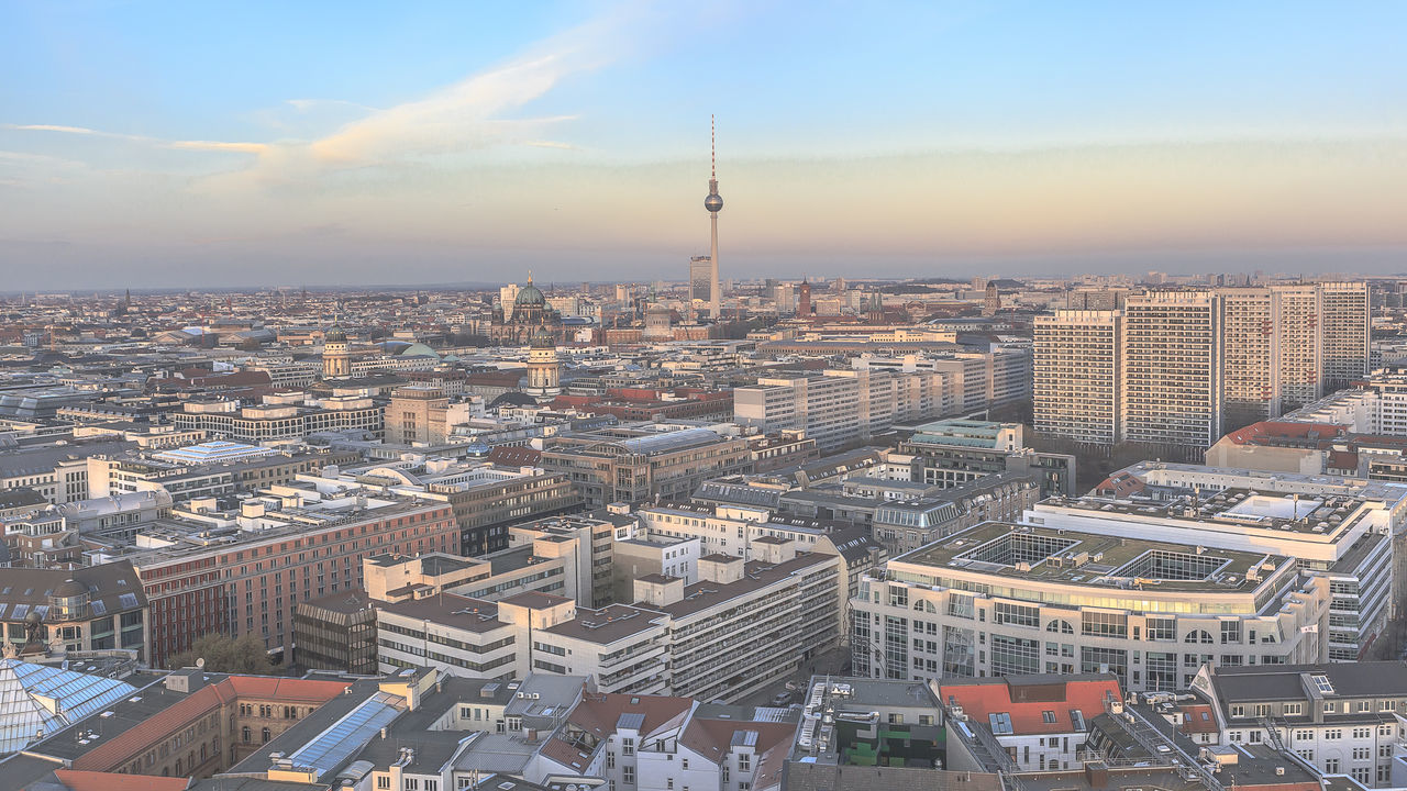 Fernsehturm amidst cityscape against sky during sunset