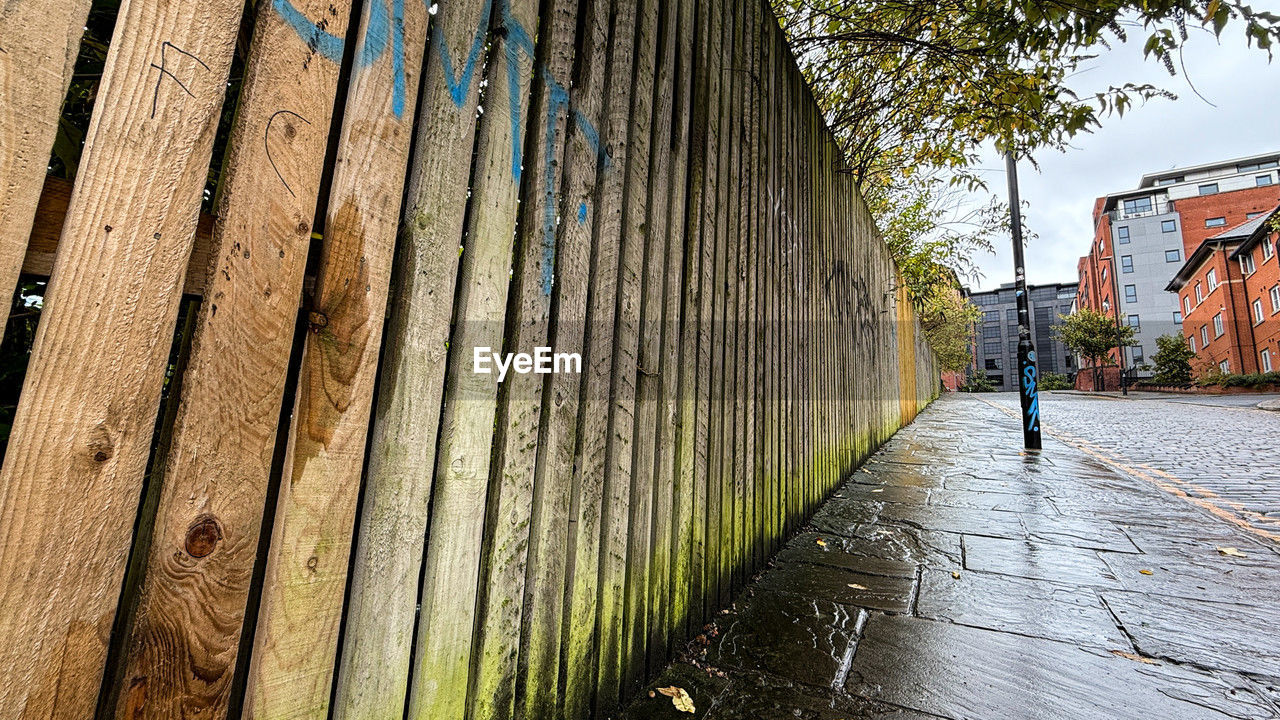 architecture, urban area, wall, built structure, wood, building exterior, day, nature, tree, road, footpath, plant, city, street, building, outdoors, one person, house, wall - building feature, fence, sunlight, walkway, men, lifestyles, walking, water