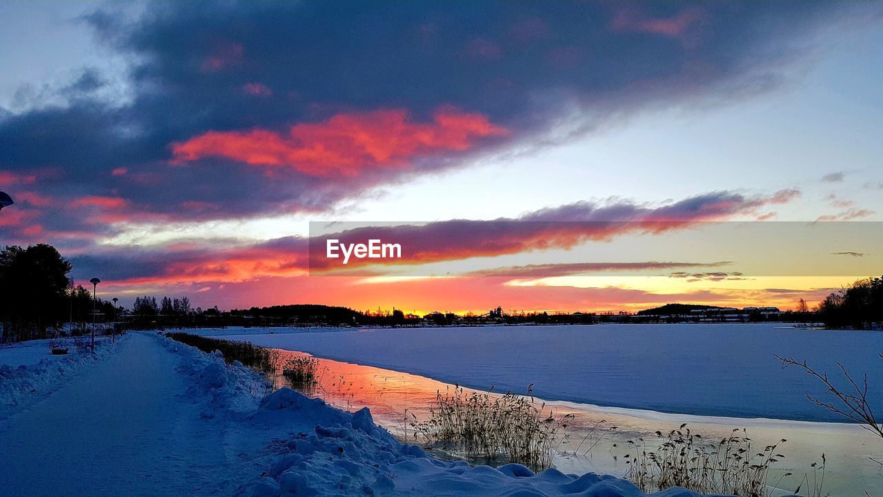 SCENIC VIEW OF LAKE AGAINST ORANGE SKY DURING WINTER