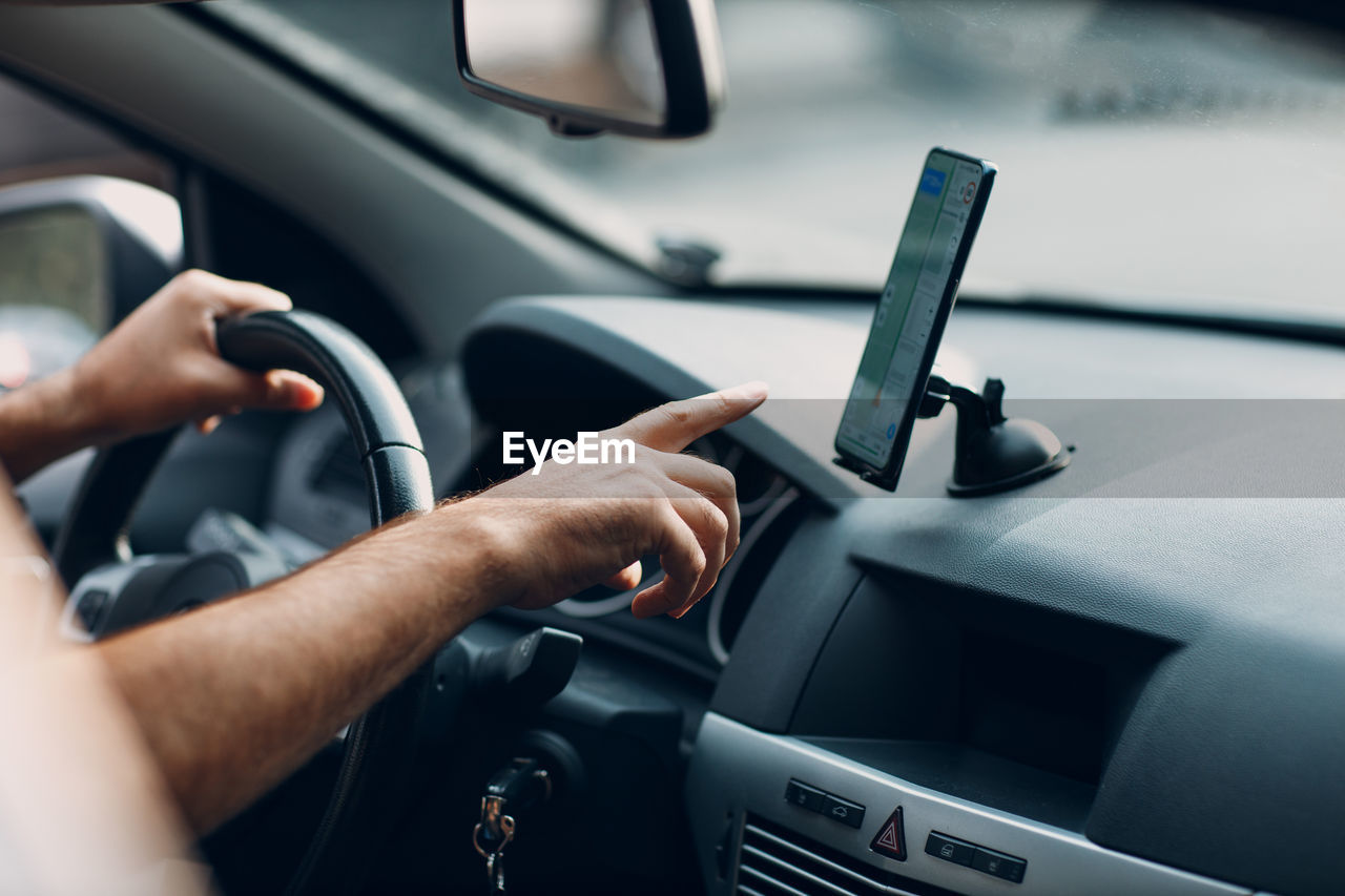 cropped image of man using mobile phone in car