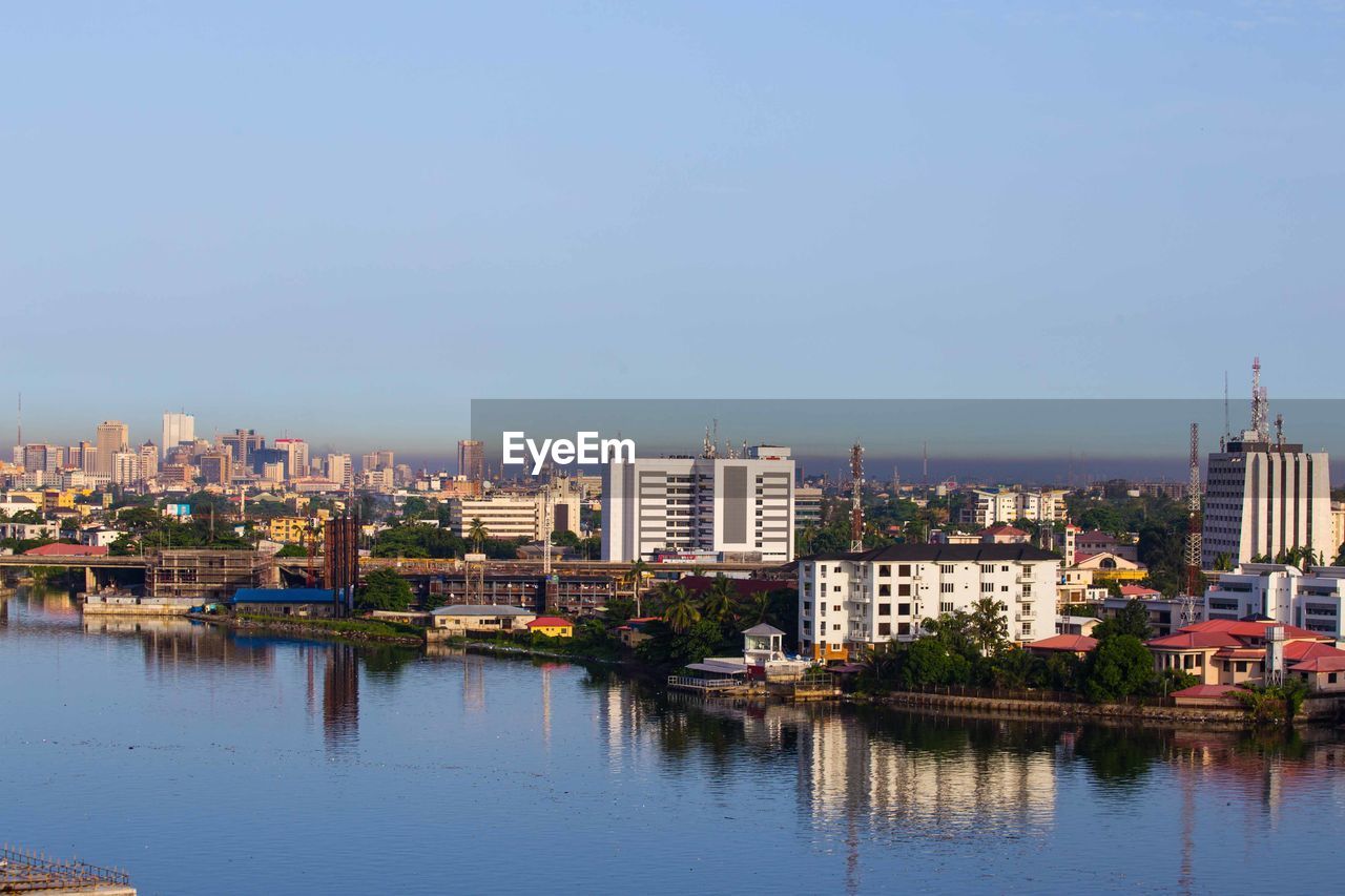 View of cityscape by river against sky