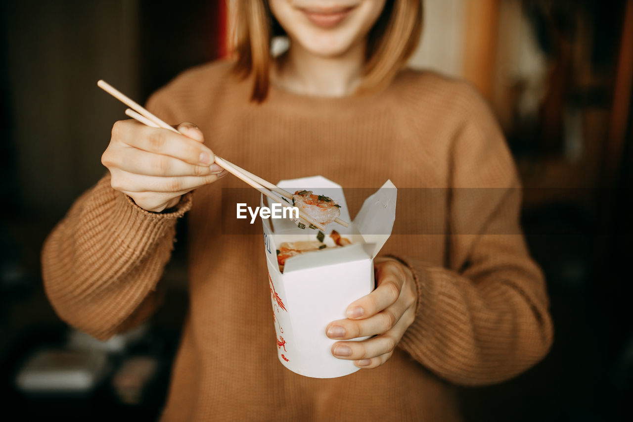 Midsection of woman eating food at home