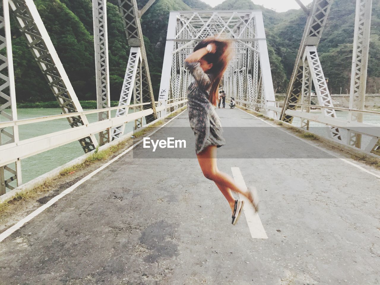 Full length of woman jumping on bridge