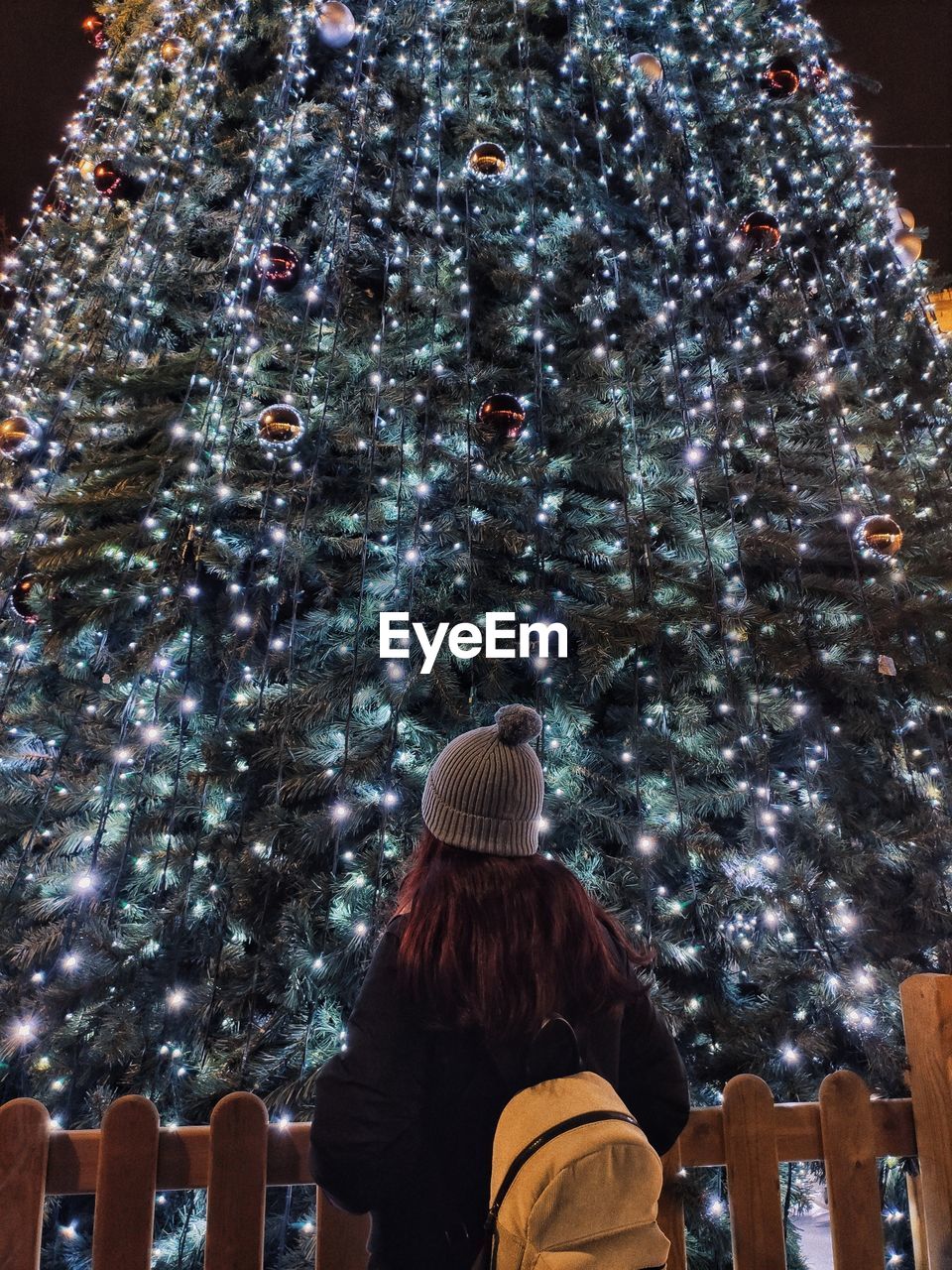 Rear view of woman standing against christmas tree at night
