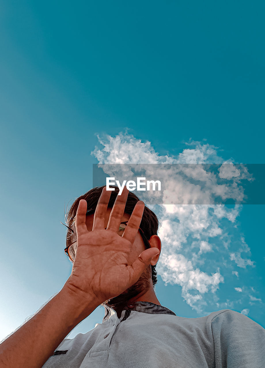 LOW ANGLE VIEW OF PERSON AGAINST BLUE SKY