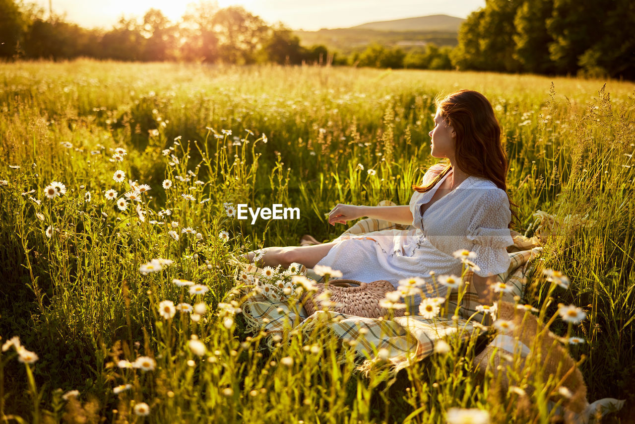 side view of woman sitting on grassy field