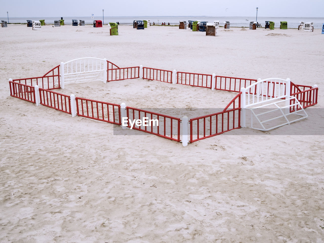 North sea beach with a small fenced beach ball field and view over the wadden sea to the horizon.