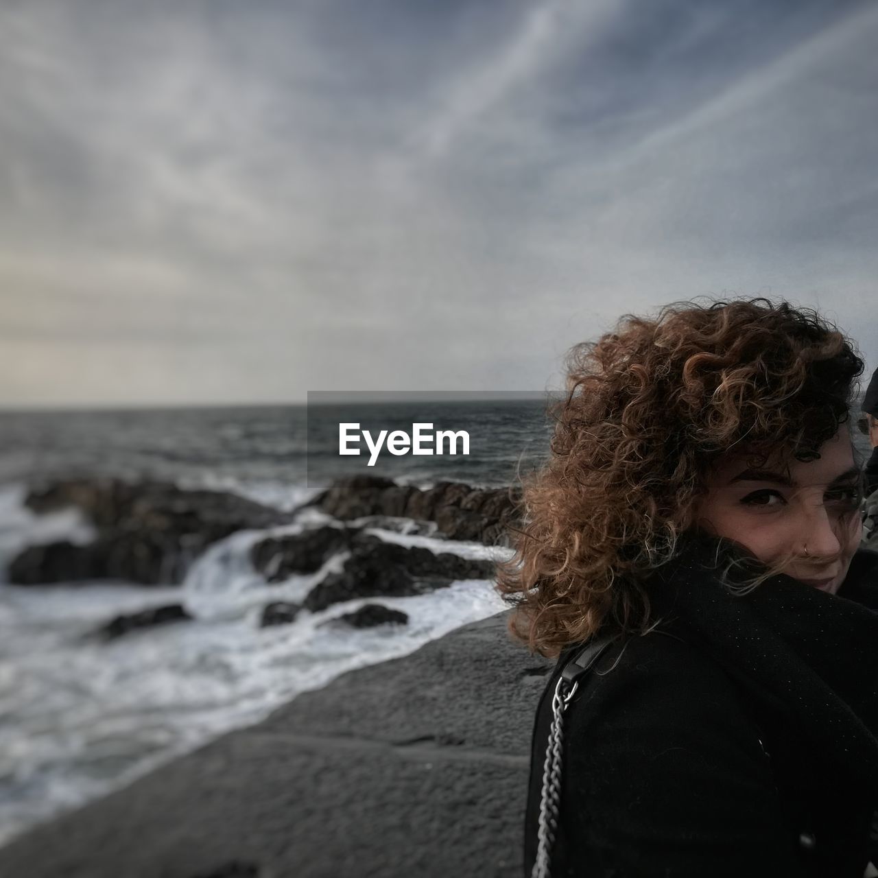 Portrait of beautiful young woman on beach against sky