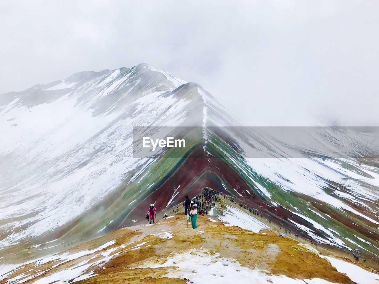 PEOPLE WALKING ON SNOWCAPPED MOUNTAINS AGAINST SKY