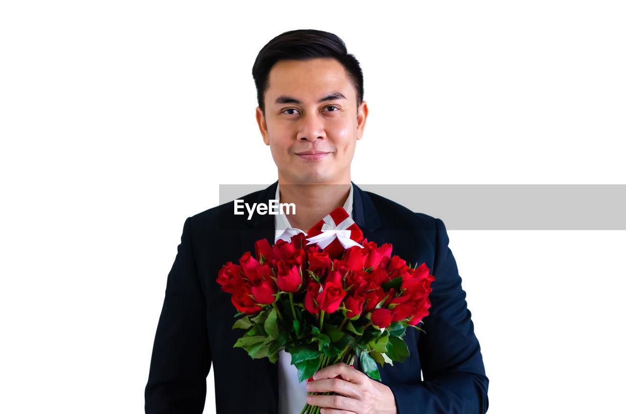 PORTRAIT OF A YOUNG MAN HOLDING RED FLOWER