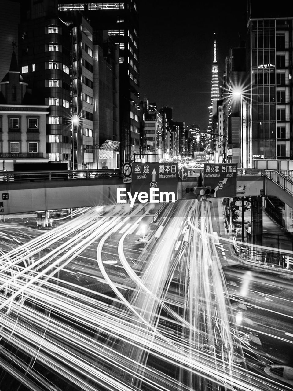 Light trails on road by buildings in city at night