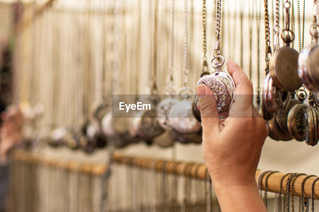 Cropped hand of person holding pocket watch at store