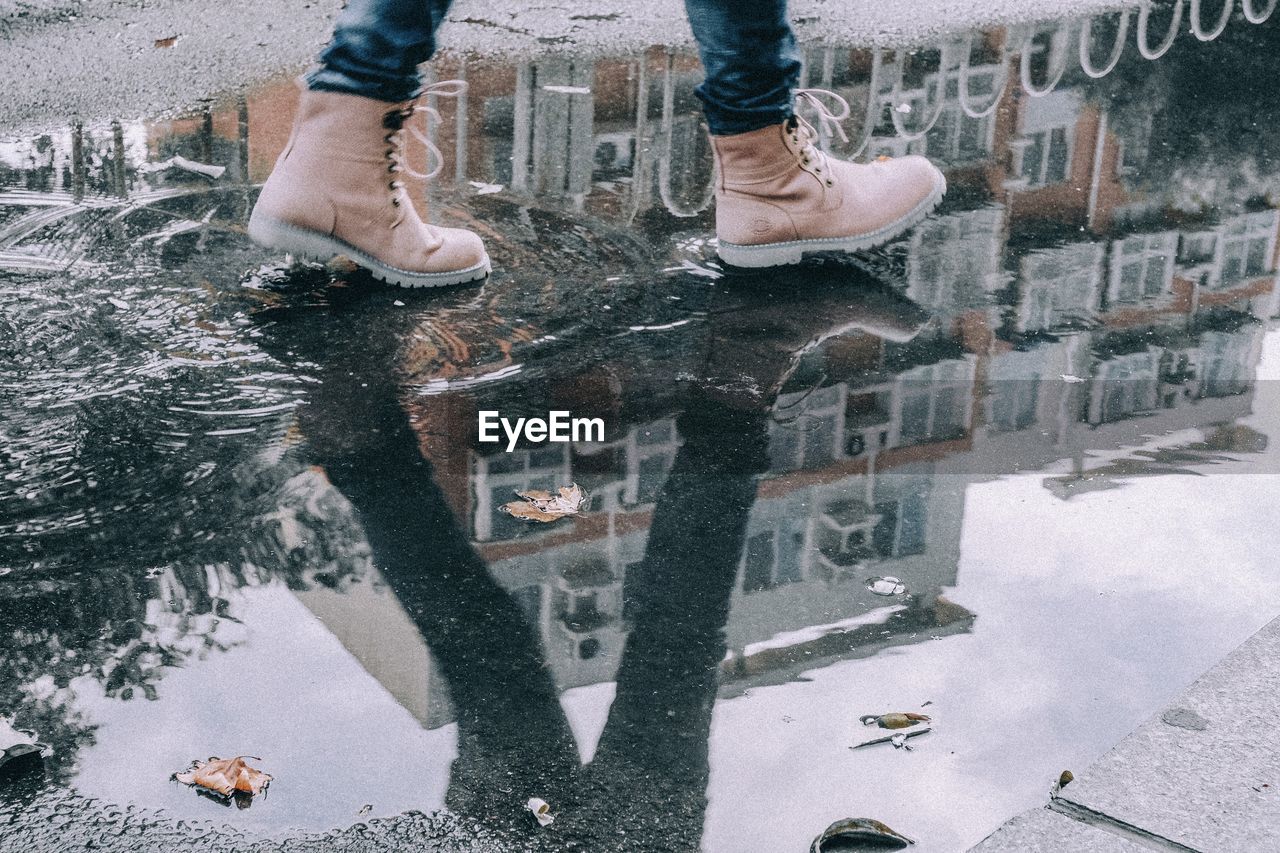 Low section of person with reflection in puddle