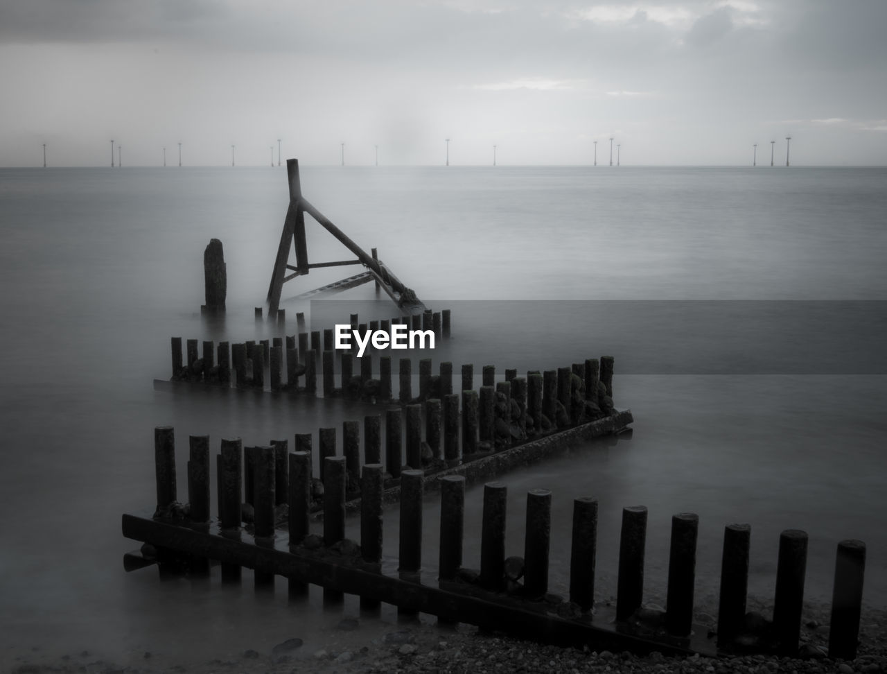 High angle view of wooden posts in sea during foggy weather