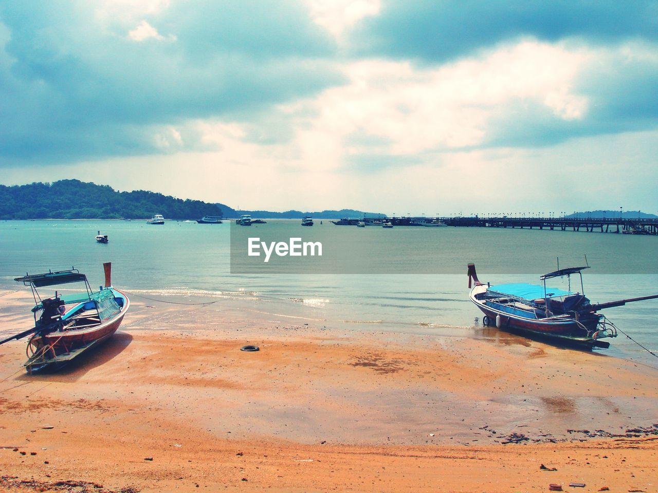 Boats moored on shore at beach against sky