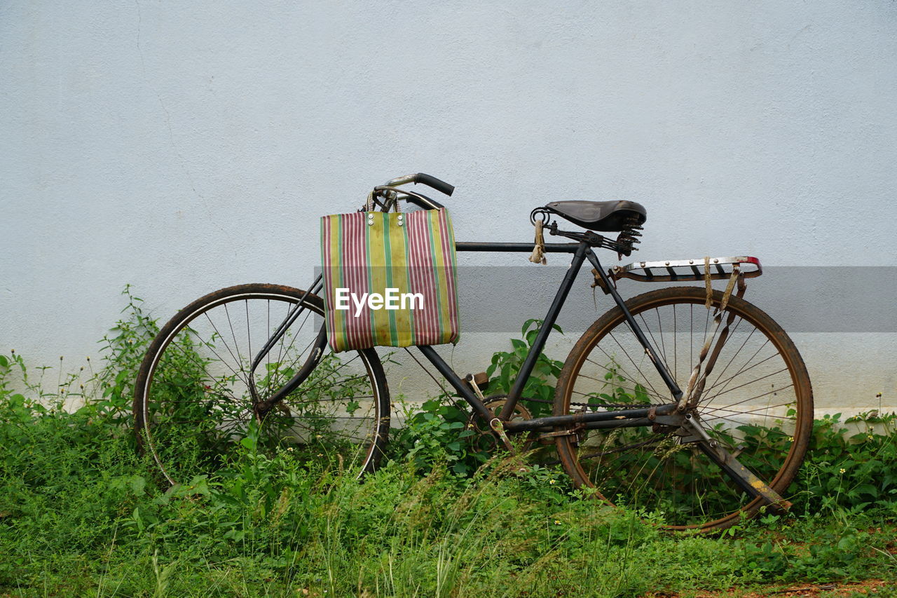 Bicycle on grass against white wall