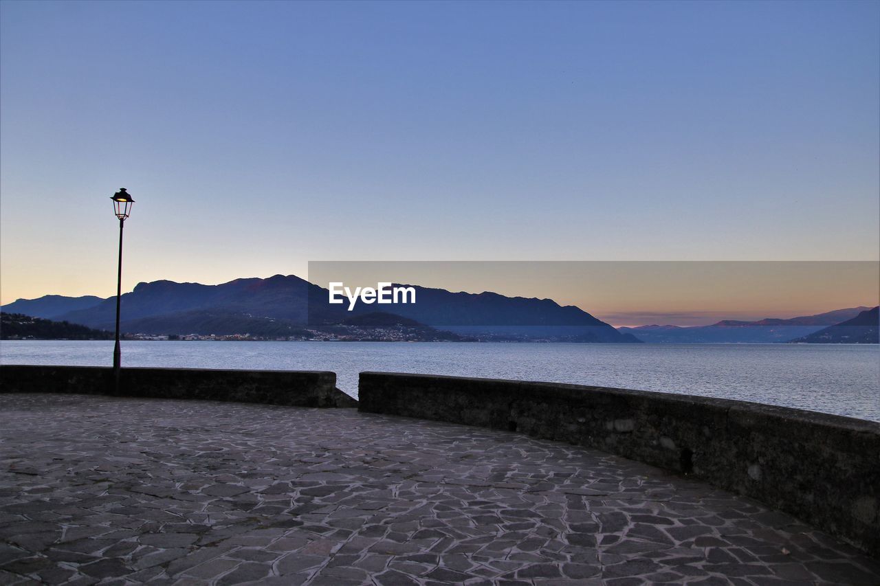 sky, horizon, mountain, sea, ocean, water, scenics - nature, dusk, morning, coast, nature, sunrise, beauty in nature, shore, reflection, land, tranquility, environment, clear sky, landscape, tranquil scene, mountain range, beach, wave, no people, travel destinations, blue, travel, outdoors, snow, body of water, sunlight, cloud, winter, copy space, idyllic, street, tourism, architecture, non-urban scene