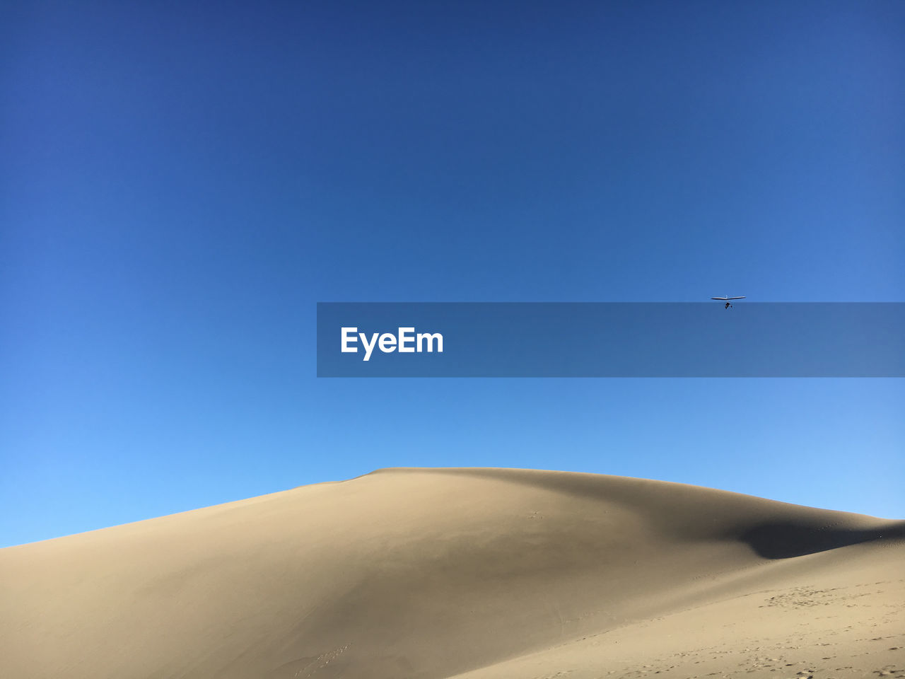 LOW ANGLE VIEW OF AIRPLANE FLYING OVER DESERT