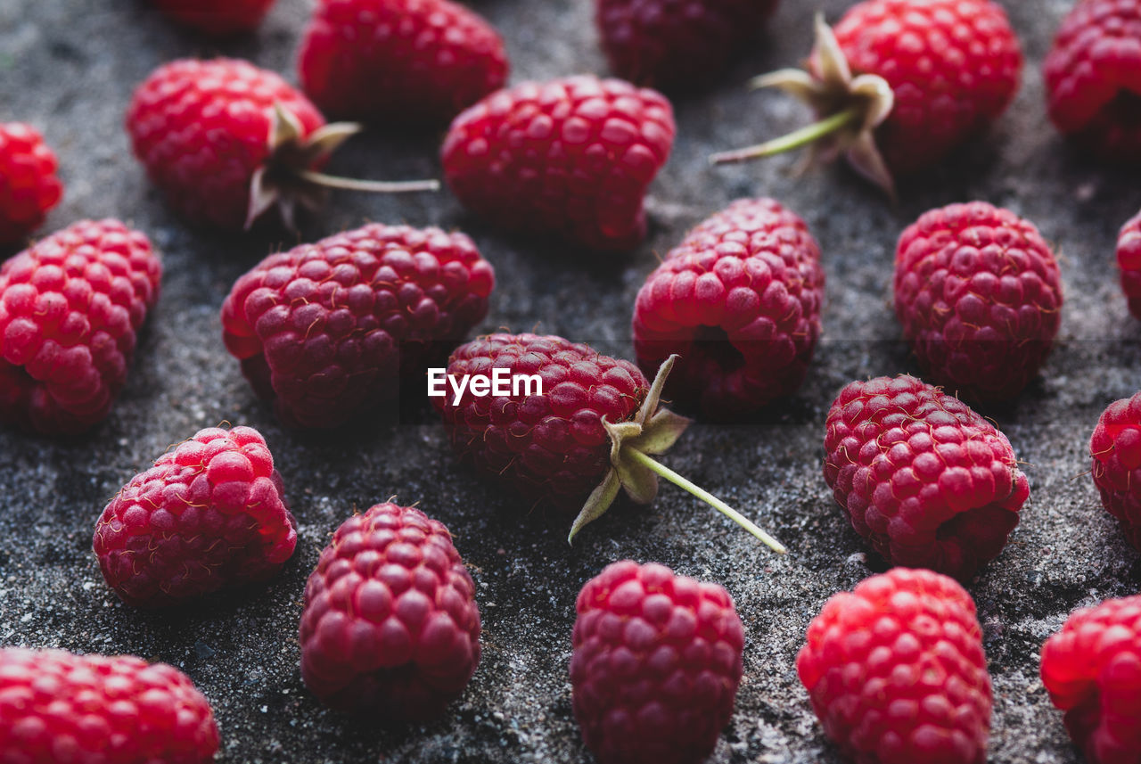 Raspberries food background - ripe harvested raspberry arranged on gray stone texture