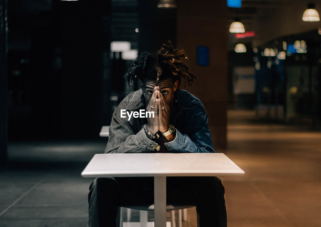 PORTRAIT OF WOMAN SITTING ON TABLE IN CITY