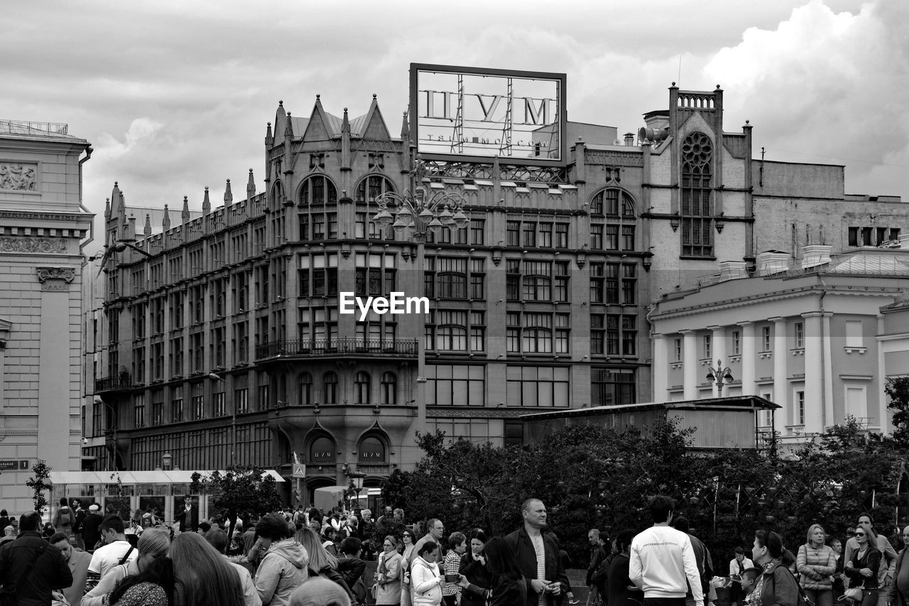 architecture, building exterior, crowd, black and white, city, built structure, group of people, large group of people, monochrome photography, monochrome, road, street, urban area, sky, building, cityscape, adult, men, city life, women, downtown, nature, lifestyles, metropolis, cloud, travel destinations, history, the past, outdoors