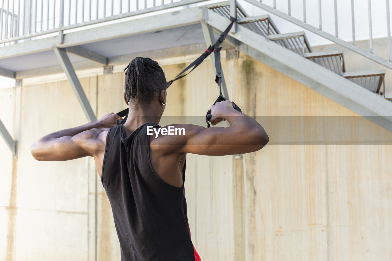 Man exercising with suspension straps hanging on staircase