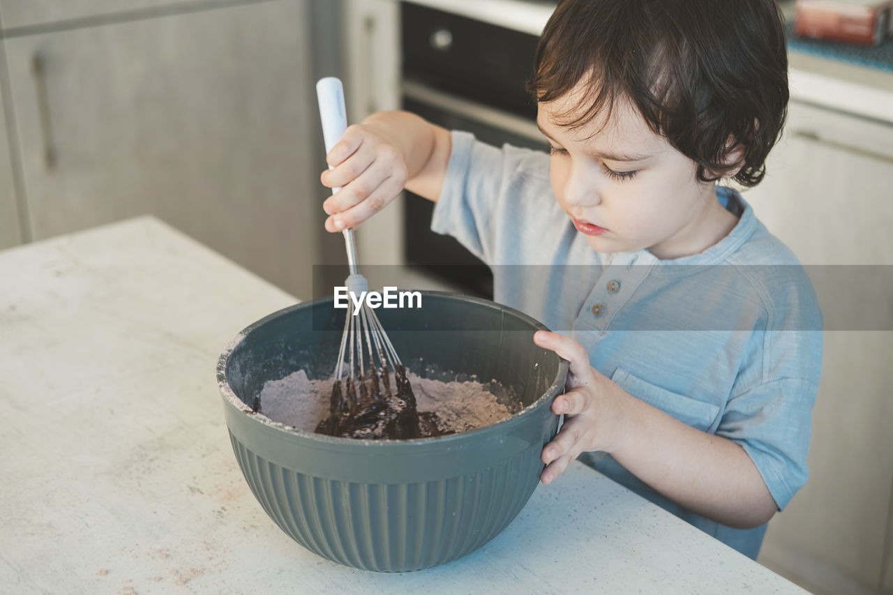 A little boy is cooking in the kitchen.