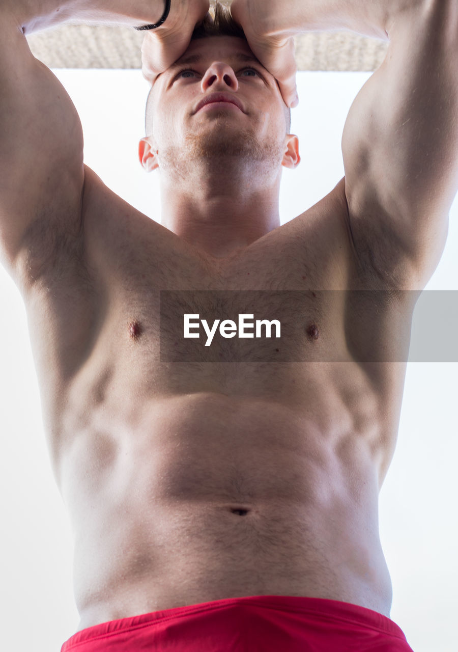 Low angle view of shirtless muscular man standing against clear sky