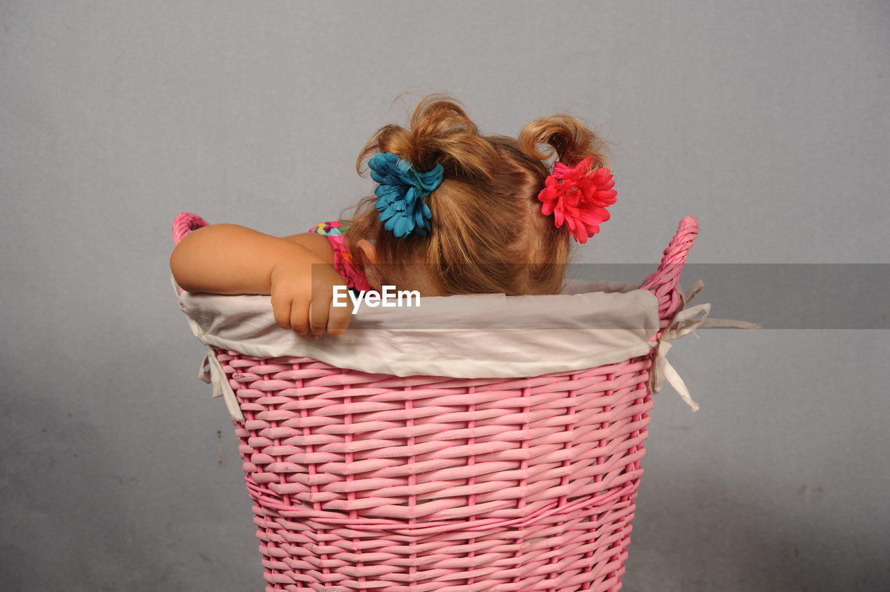 Girl sitting in basket against wall
