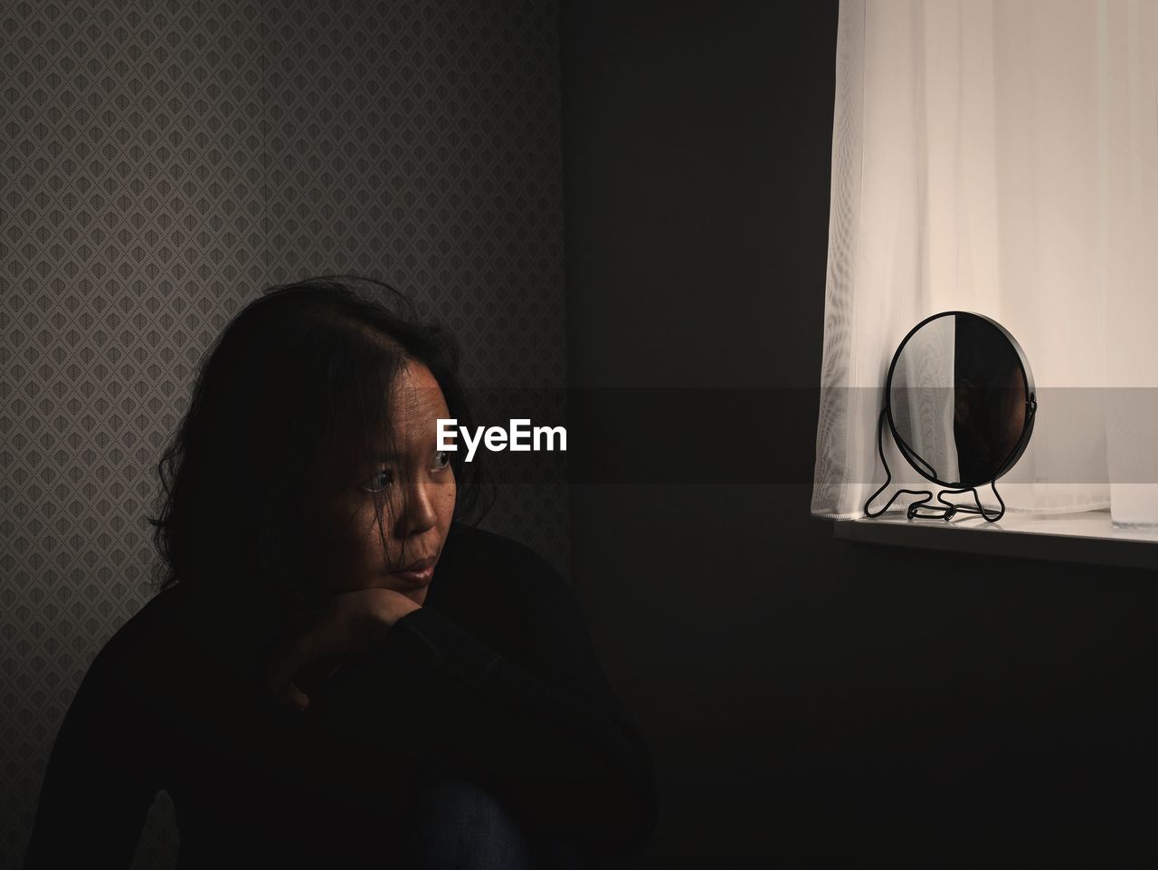 Woman with reflection in mirror sitting at home