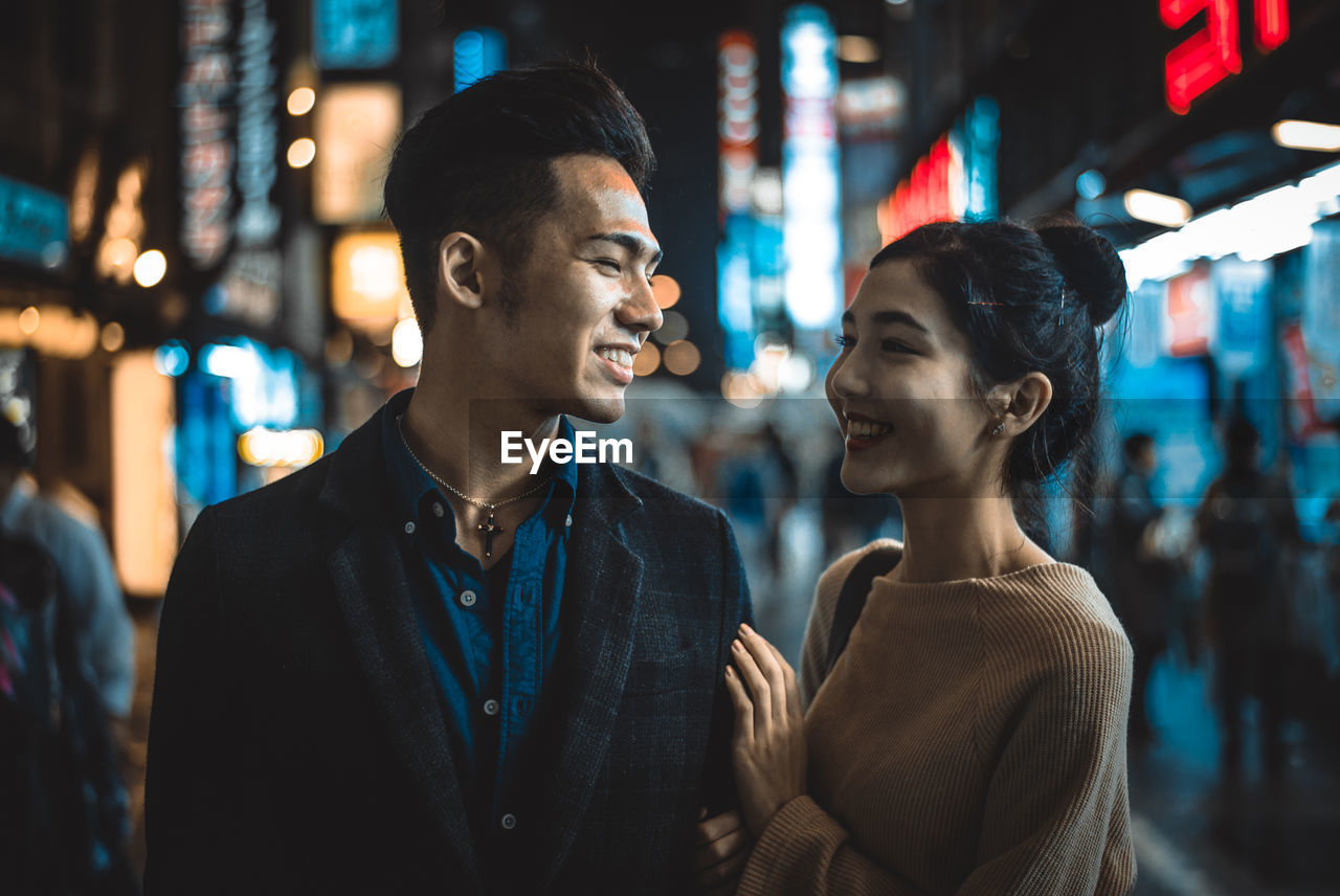 Smiling couple standing on street in city at night