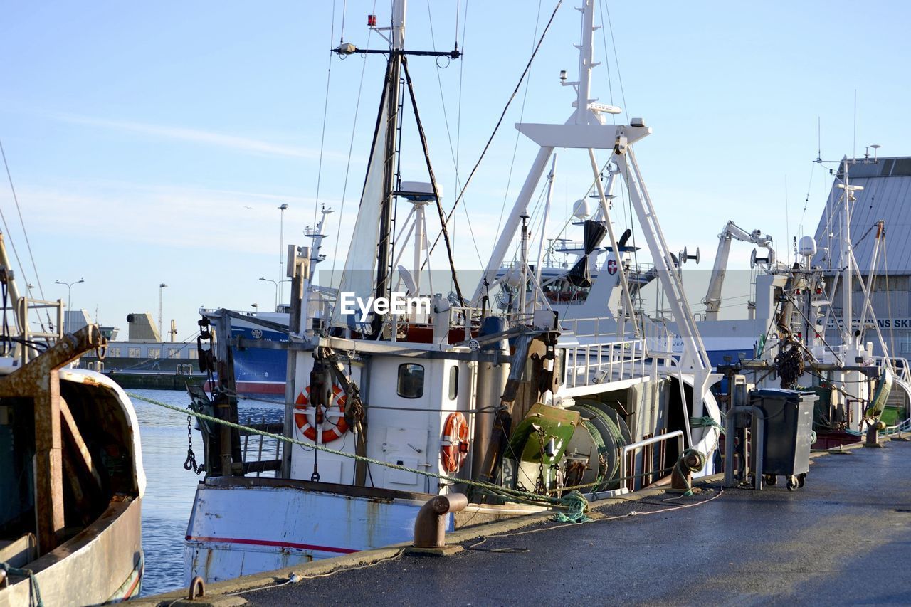 Boats moored at harbor against sky