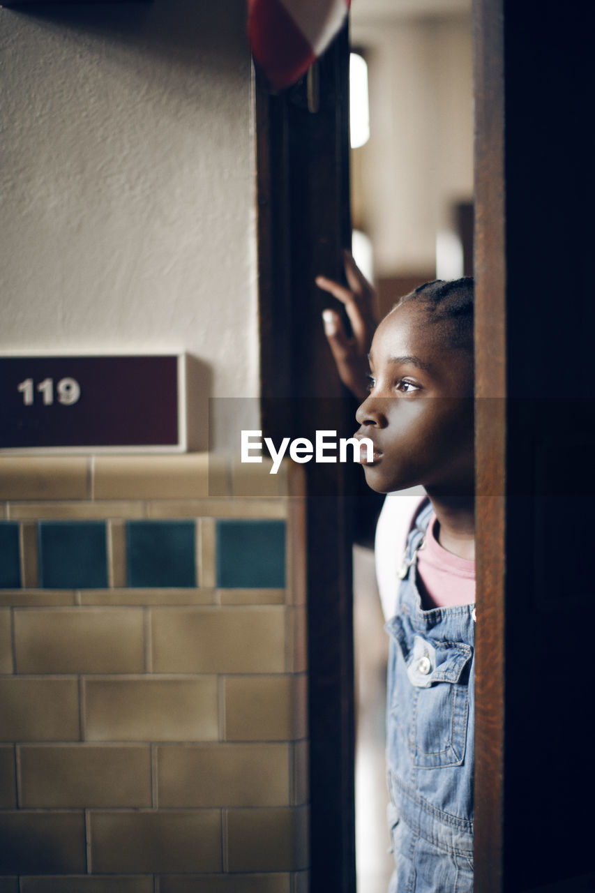 Thoughtful girl standing at doorway in school