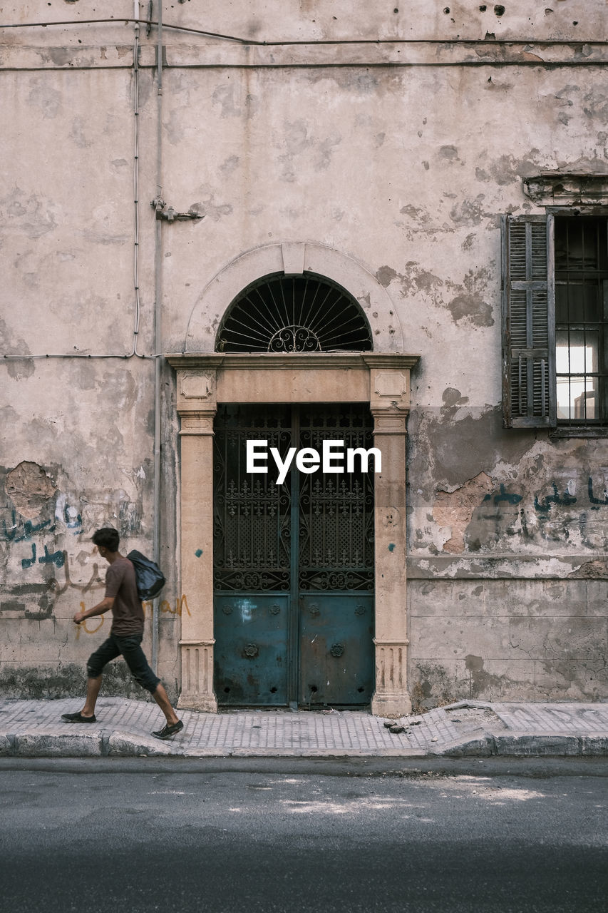 Side view of man walking by classically designed building