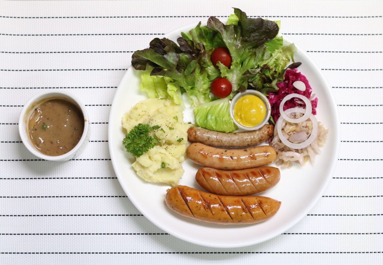 Directly above shot of sausages with salad and mashed potatoes on table